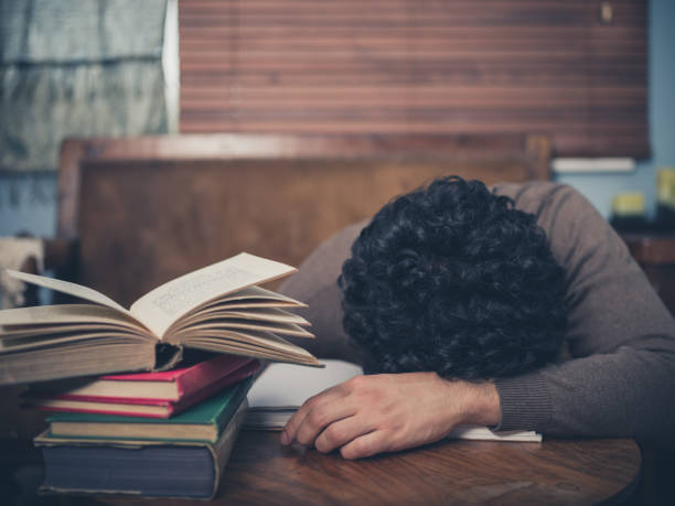 istock Tired student fallen asleep surrounded by books 471905176