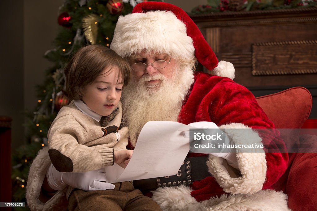 Boy going over naughty nice list with Santa Boy going over naughty nice list with Real Santa Claus. This pictures a horizontal composition.  Santa Claus Stock Photo