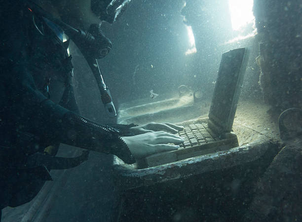 Diver in a submerged and ruined airplane using laptop