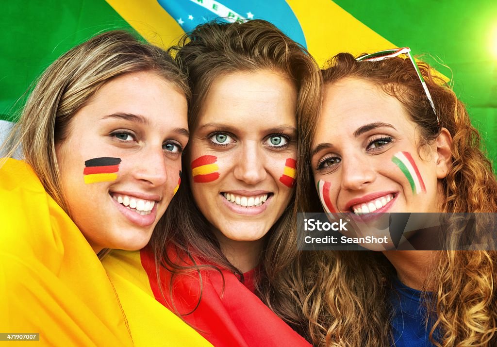 Italian, German and Spanish Fans. Brazilian Flag in the Background. . Fan - Enthusiast Stock Photo