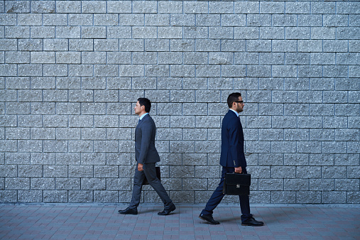 Two businessmen walking in opposite directions