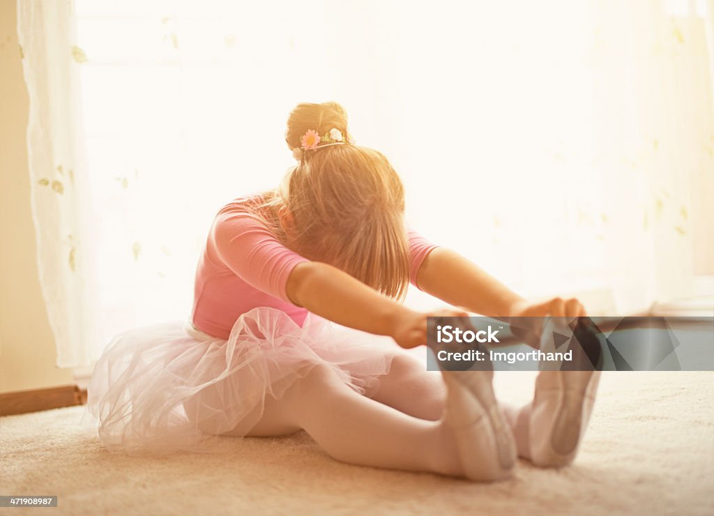Little ballerina practicing at home Little ballerina stretching at home, near the window. Back Lit Stock Photo