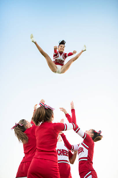 cheerleader throw-up-mädchen in der luft - arms outstretched teenage girls jumping flying stock-fotos und bilder