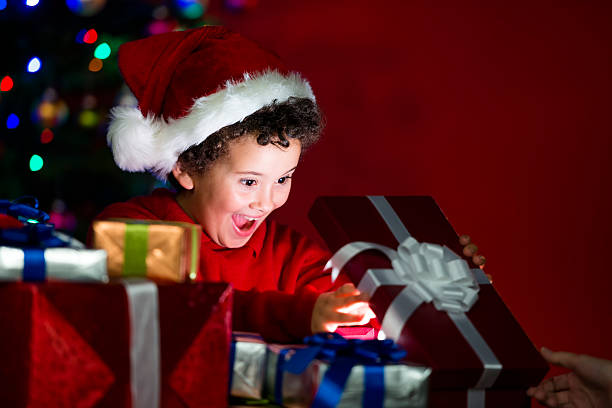 istock Excited child opening a gift under the Christmas tree 471910775
