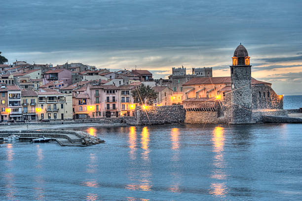 Mediterranean harbour at night The beautiful village and harbour at Collioure, Languedoc-Roussillon, France showing the famous clocktower and chapel, and the Mediterranean Sea collioure stock pictures, royalty-free photos & images