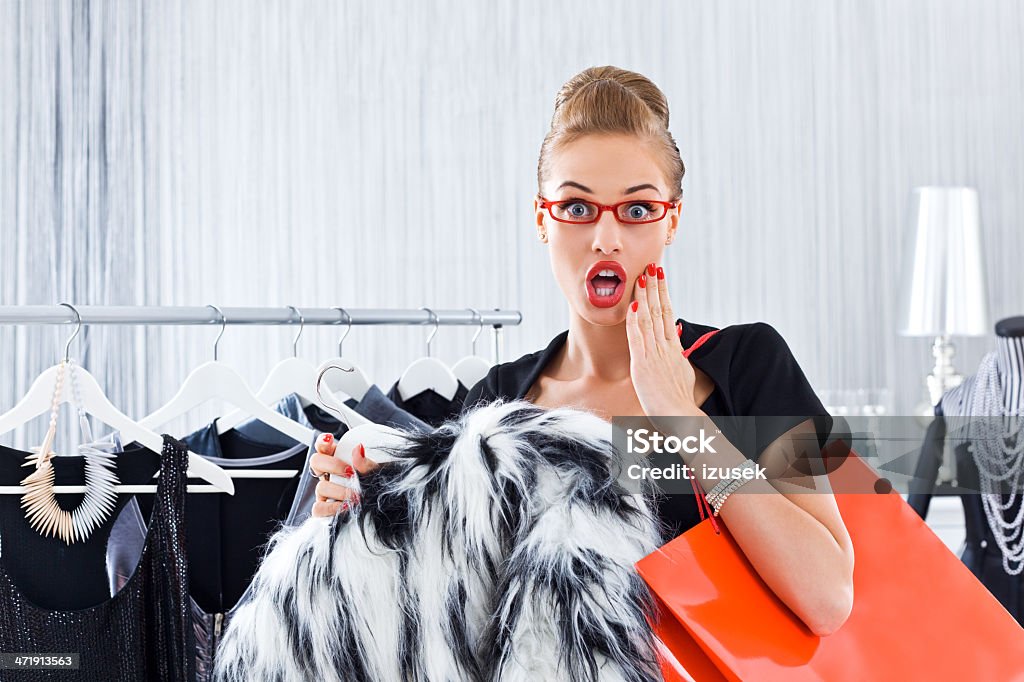 Woman during shopping Portrait of surprised young adult woman during shoppping in a luxury boutique, staring at the camera with mouth open. Coathanger Stock Photo