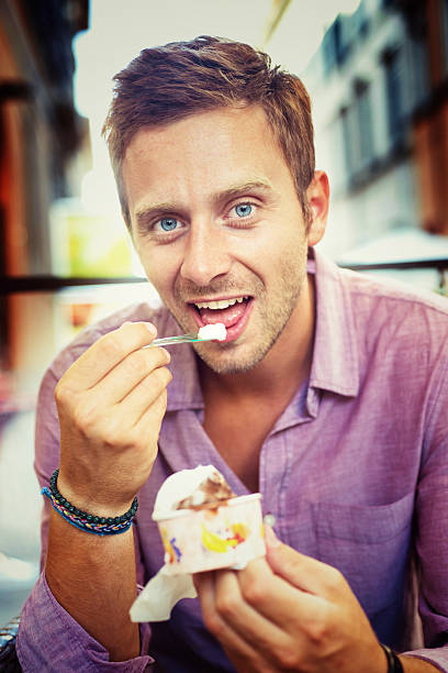 souriant homme manger une glace - ice cream parlor ice cream dessert italian culture photos et images de collection