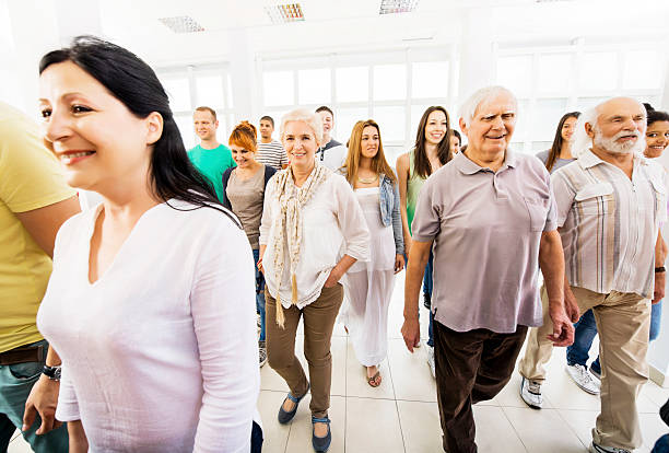 Large group of mixed age people walking indoors.  