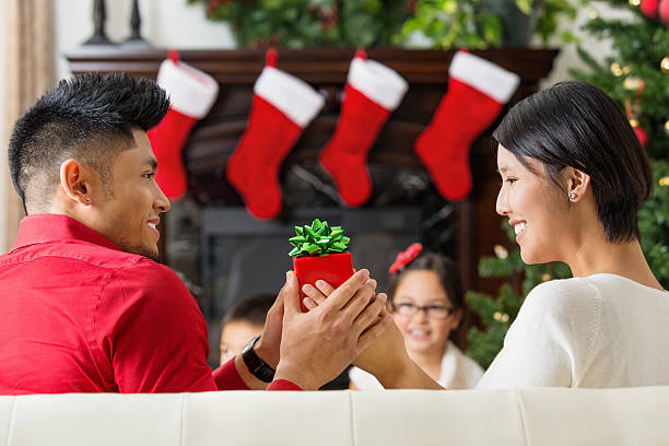 Couple exchanging Christmas gifts at home Couple exchanging Christmas gifts at home.  asian women in stockings stock pictures, royalty-free photos & images