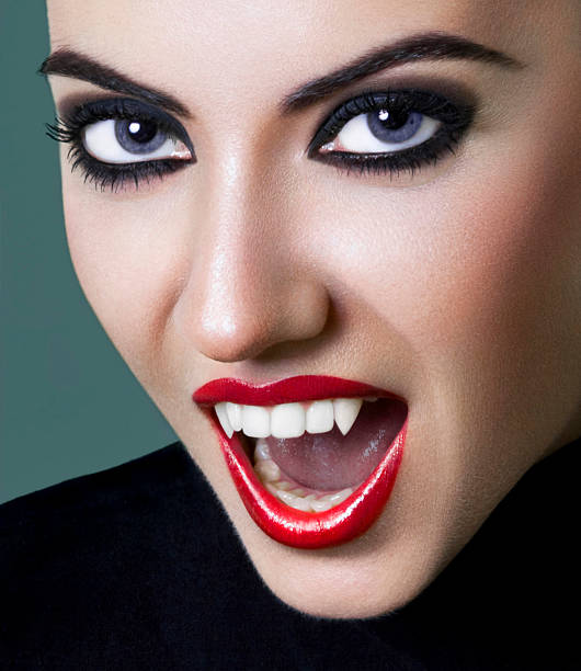 Pretty, young female dressed as a vampire Close-up portrait of a vampire girl showing her fangs vampire woman stock pictures, royalty-free photos & images