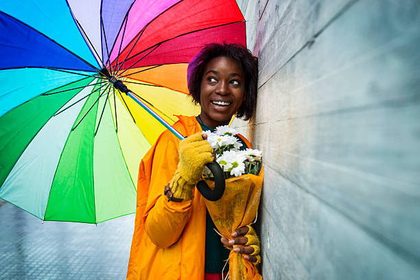 felice giorno di pioggia in città - candid women african descent umbrella foto e immagini stock