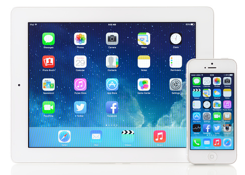 İstanbul, Turkey - October 29, 2013: The New iPad and iPhone 5 displaying iOS 7 homescreen on a white background. iOS 7 is a mobile operating system designed by Apple Inc. It was released in Fall 2013. The New iPad the digital tablet produced by Apple Computer, Inc. The iPhone 5 is a touchscreen smartphone developed by Apple Inc.