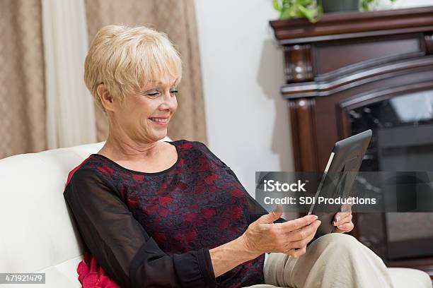 Mujer Senior Usando Tableta Digital De Dispositivo En Su Foto de stock y más banco de imágenes de Abuela