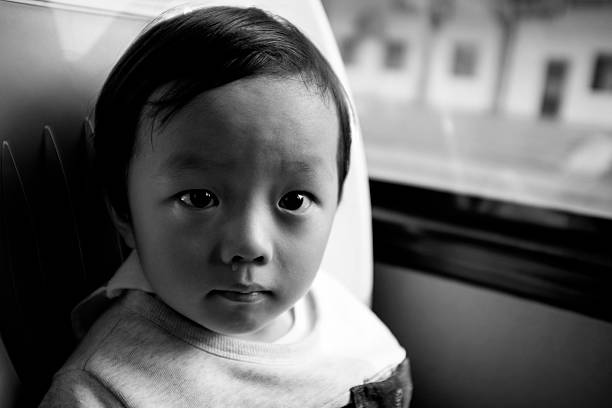 Little boy waiting by window for stop raining. Loneliness and waiting concept. Rainy day. black and white