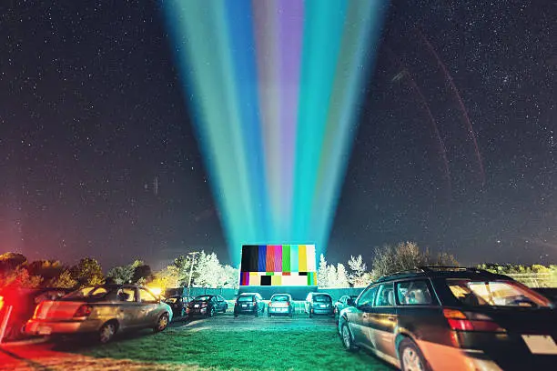 Drive in movie goers enjoy a screening under clear Autumn skies. Composite image with test pattern. Long exposure.