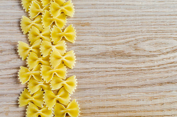 makaron farfalle tle niepoddane obróbce cieplnej - bow tie pasta italian cuisine bow heap zdjęcia i obrazy z banku zdjęć