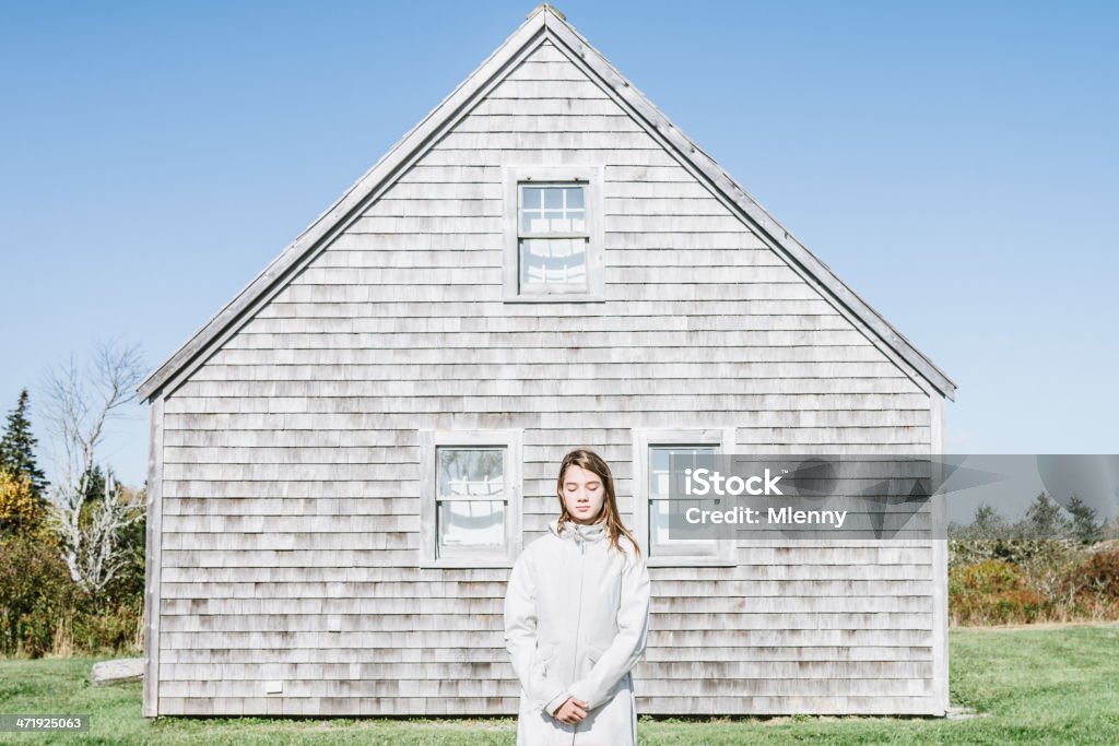 Silence, Nova Scotia Girl Portrait Young girl in white trenchcoat standing with closed eyes in front of her home, thinking, listening, enjoying the silence and sun. Tranquility, Silence, Abstract Concept Portrait. Nova Scotia, Canada. Nova Scotia Stock Photo