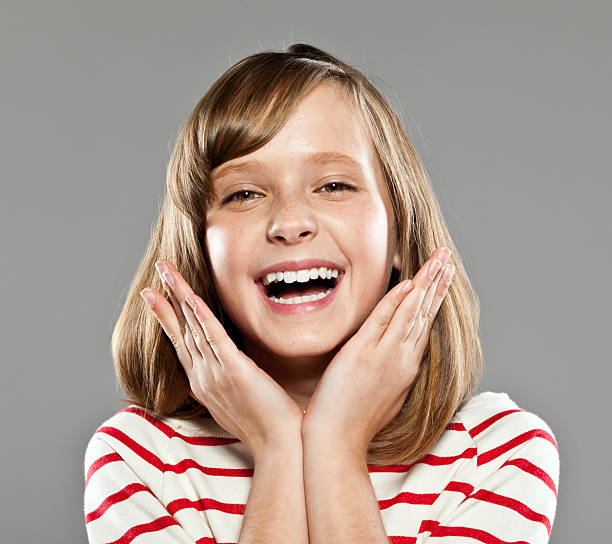 Portrait of cute girl wearing striped blouse laughing at camera, Studio shot.