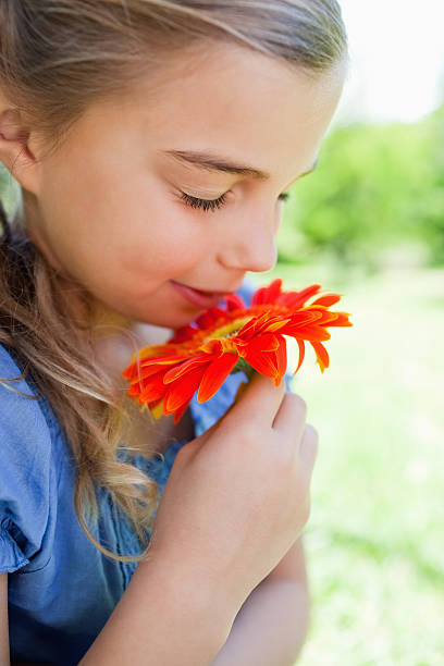 istock Young girl standing up while smelling a flower 471927093