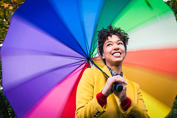 istock Smiling woman with a multi colored umbrella 471927571