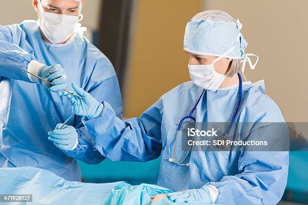 Surgical Technician Handing Instruments To Surgeon In Operating Room Stock Photo - Download Image Now