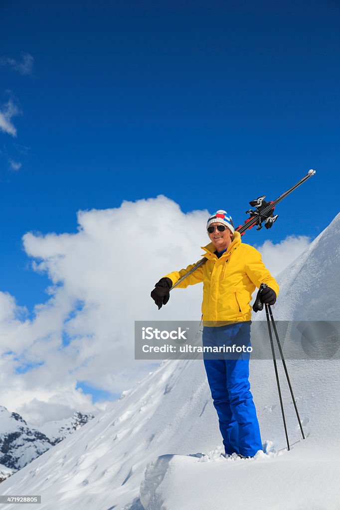 Snow Skiers Senior snow skier carrying skis. High mountain snowy landscape. Livigno mountain range, Alps. It is located in the Italiy. Active Lifestyle Stock Photo