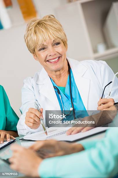 Senior Doctor Or Nurse In Hospital Staff Meeting Stock Photo - Download Image Now - Administrator, Adult, Blond Hair