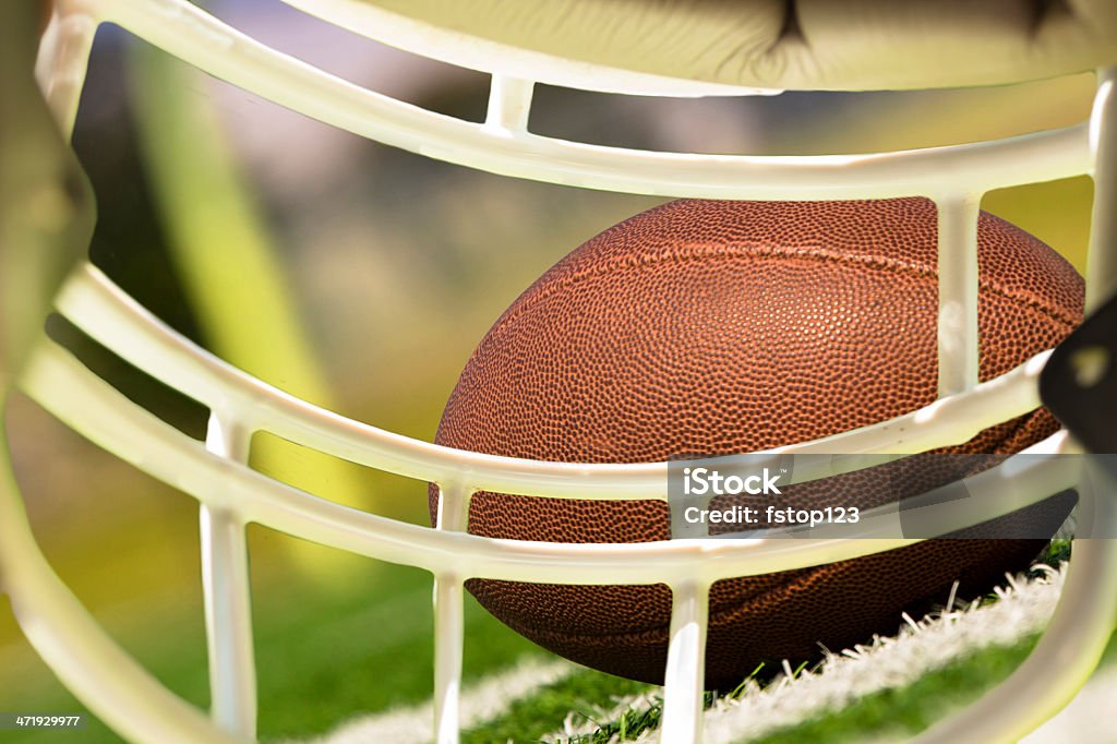 Sports: Football helmet perspective of ball, field. Football helmet perspective of the field and football as looking through the face mask. American Culture Stock Photo