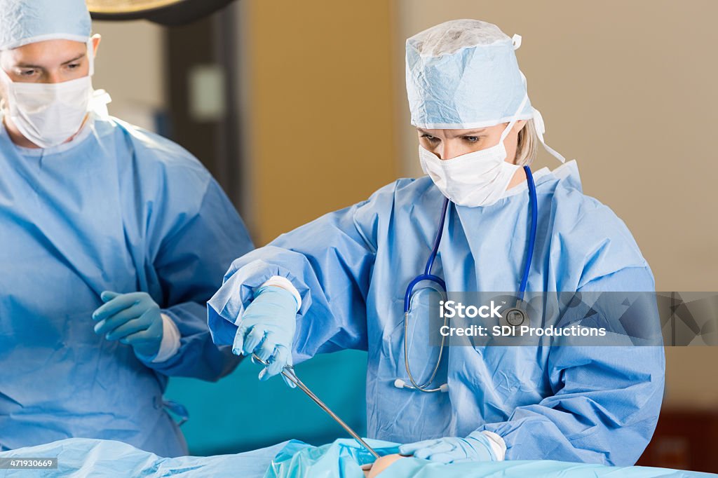Cirujano realiza procedimiento en paciente en el hospital - Foto de stock de Cirujano libre de derechos