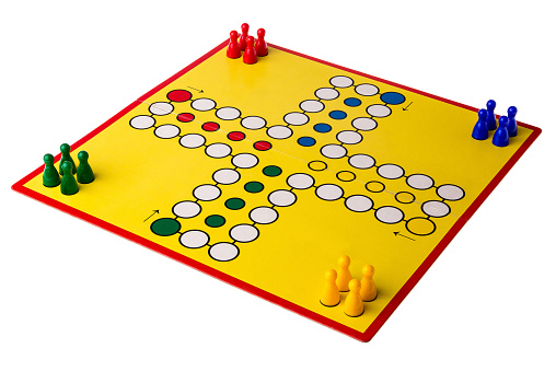 Yellow board game with four different colored game pawns on it.