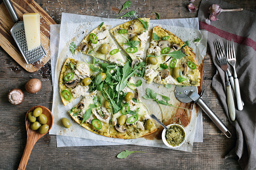Slices of pizza with chicken, mozzarella, olives, mushrooms and pesto sauce