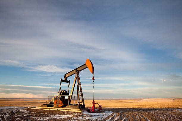 Pumpjack on the Prairie A red pumpjack in winter. Panorama. oil pump oil industry alberta equipment stock pictures, royalty-free photos & images