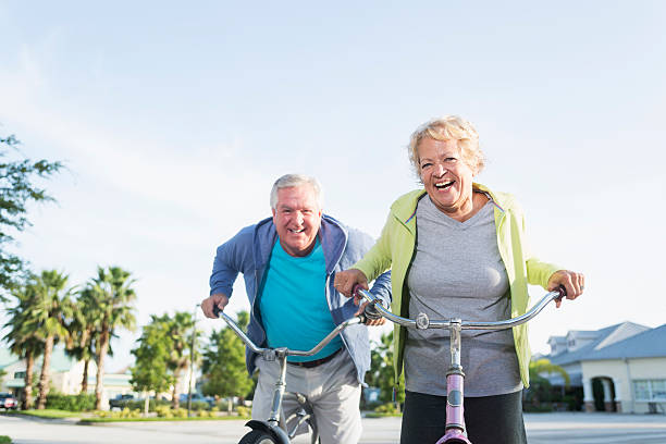 montar bicicletas de pareja senior - action mature adult bicycle senior couple fotografías e imágenes de stock