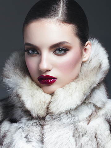 Portrait of beautiful woman wearing fur coat. Professional make-up and hairstyle. High-end retouch.