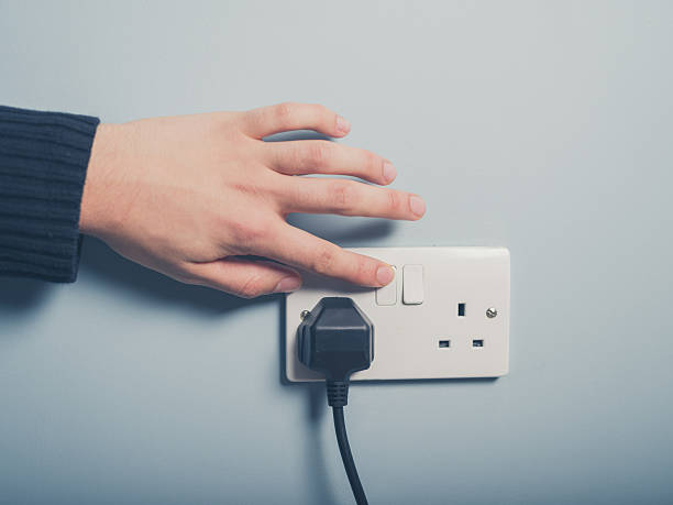 Male hand pressing a power switch on the wall A male hand is pushing a switch on a wall socket electric plug stock pictures, royalty-free photos & images