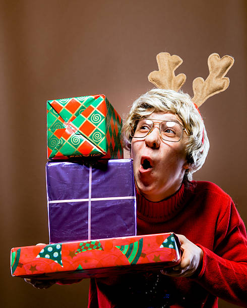 Christmas Reindeer Nerd Boy Receives Stack of Gifts Nerdy Christmas reindeer boy receives large stack of gifts. vintage nerd with reindeer sweater stock pictures, royalty-free photos & images