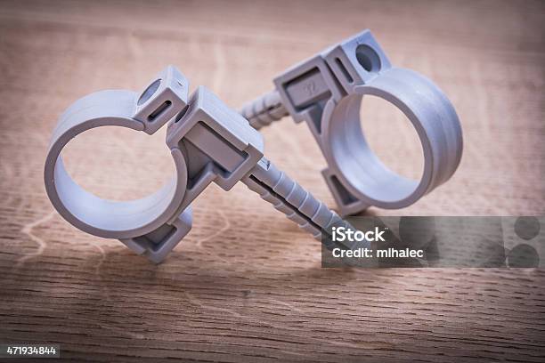 Two Polypropylene Pipe Fixators On Wooden Board Stock Photo - Download Image Now - 2015, Close-up, Construction Equipment