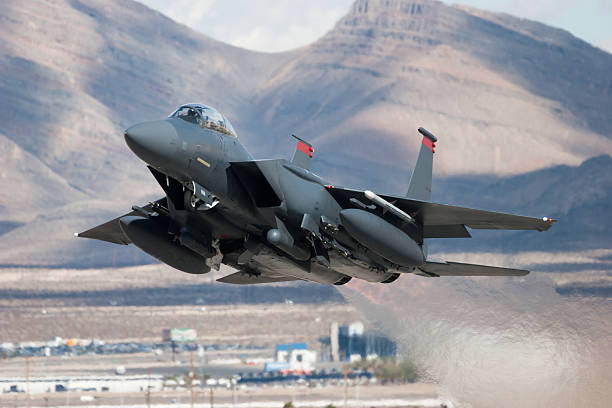 F-15E Strike Eagle flying past mountains An F-15E Strike Eagle taking off. military airplane photos stock pictures, royalty-free photos & images