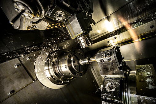 Close up for the automatic cutting machine carving holes in a metal detail at the plant. Metal details production with metal shavings flying into the sides.