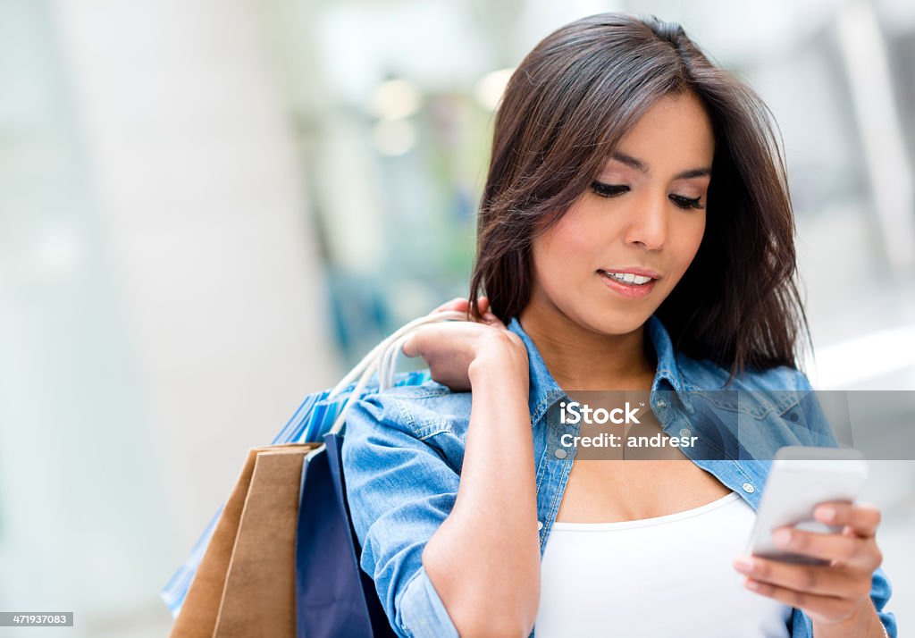 Woman checking her cell phone Portrait of a beautiful woman checking her cell phone after shopping 20-24 Years Stock Photo