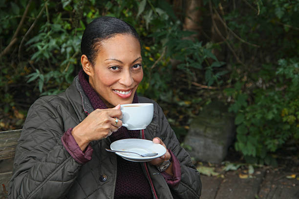 istock Lady holding a coffee cup & smiling towards the camera. 471938813