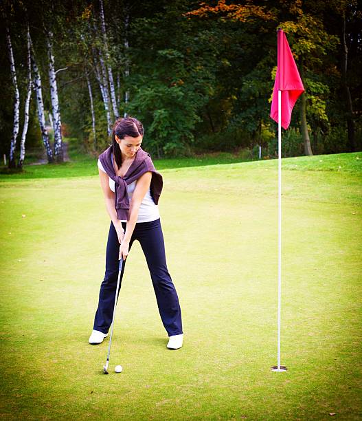 woman ゴルフ選手のトレーニングボールでパッティング練習用グリーンをカップ - golf green practicing sports training ストックフォトと画像