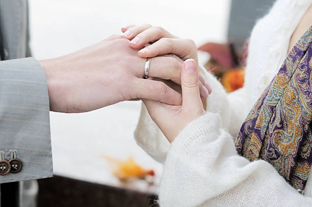 istock Groom putting a wedding ring on bride 471942043