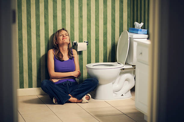 Young woman in pain on bathroom floor stock photo