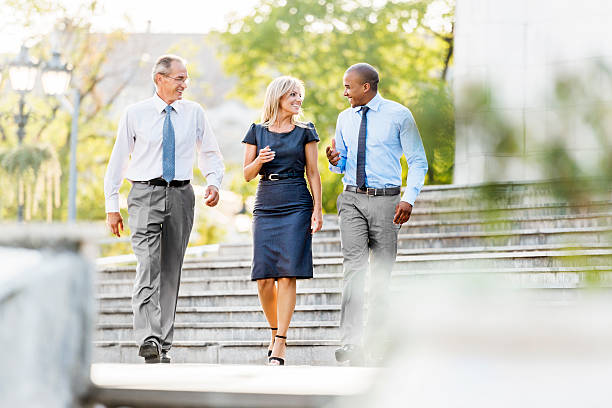 Three business people walking outdoors. Three cheerful business people walking in the street and communicating.    colleagues outside stock pictures, royalty-free photos & images