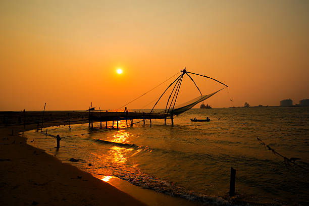 Kochi chinese fishnets and the boat with fishermen on sunset  in Kerala. Fort Kochin, Kochi,  South India