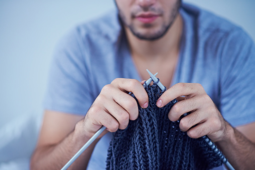 Close-up of man knitting blue sweater