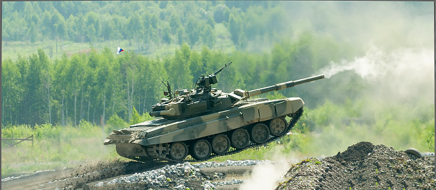 Shooting tank T-80 moving through cross-country terrain with obstacles