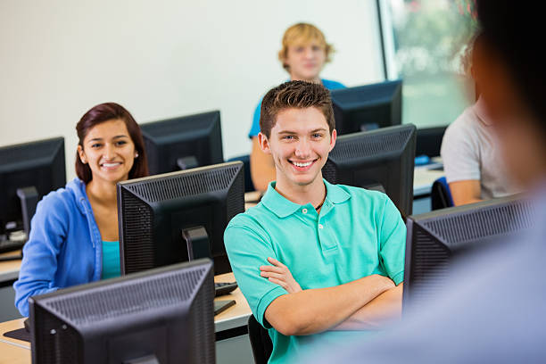 istock Happy teen students listening to instructor in computer lab 471948615