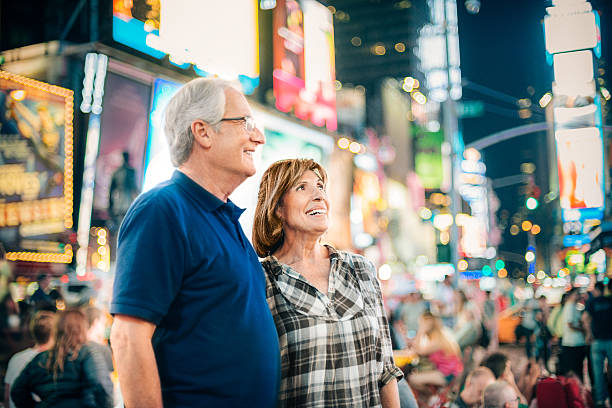 senior couple sur times square, à new york - dusk people manhattan new york city photos et images de collection